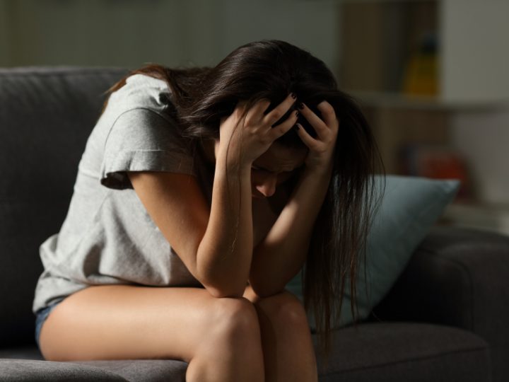 Woman sitting on a sofa with her head in her hands